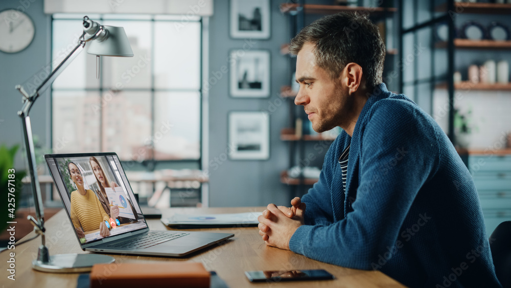 Aufkleber Handsome Caucasian Man Having a Video Call on Laptop Computer while Sitting Behind Desk in Living Room. Freelancer Working From Home and Talking to Colleagues and Clients Over the Internet.