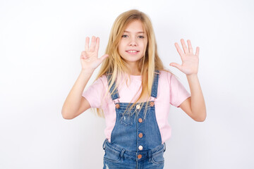 beautiful caucasian little girl wearing denim jeans overall over white background showing and...