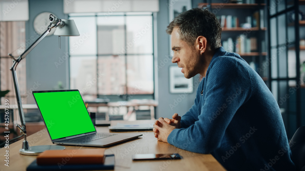 Poster handsome caucasian specialist chatting on video call on laptop with green screen mock up display at 