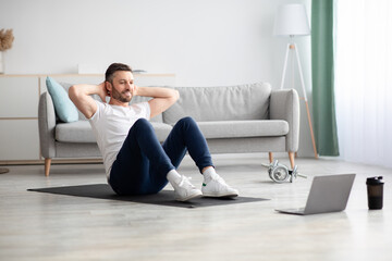 Obraz premium Smiling man working on abs, using laptop