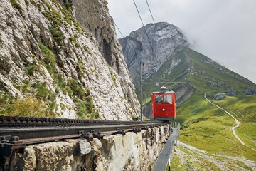 Cogwheel train passing mountain landscape of Swiss Alps.Red train on cog railway between Mount...