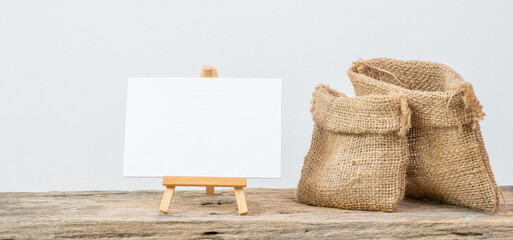 White board stand and two different size burlap bags on grunge wooden  shelf with copy space isolated over white background