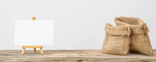 White board stand and two different size burlap bags on grunge wooden  shelf with copy space isolated over white background