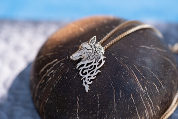 Pendant wolf head necklace golden color stainless steel shoot outside in a sunny day closeup. Selective Focus. High quality photo