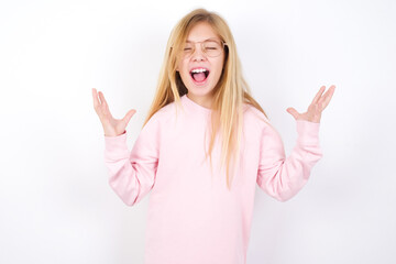 Fototapeta na wymiar Crazy outraged Beautiful caucasian blonde little girl wearing pink sweater screams loudly and gestures angrily yells furiously. Negative human emotions feelings concept