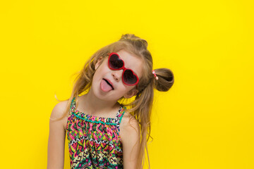 Cute little girl in sun glasses on the yellow background in the studio.