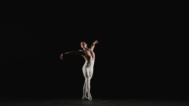 Male ballet dancer performs ballet dance elements on a black background. Slow motion