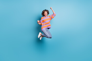 Naklejka na ściany i meble Full length body size view of attractive cheerful girl jumping rejoicing having fun isolated over bright blue color background