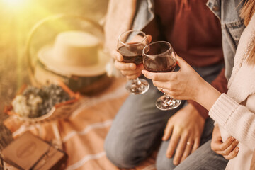 two glasses of red wine in the hands of a couple in love at a picnic, in the rays of sunlight