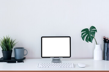 Creative workspace mockup with blank screen tablet on stand and keyboard on white top table.