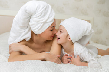 Mother and her daughter playing and hugging in the bed. Happy loving family. Happy mother's day.