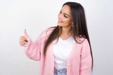 young beautiful caucasian woman wearing pink knitted jacket over white wall Looking proud, smiling...