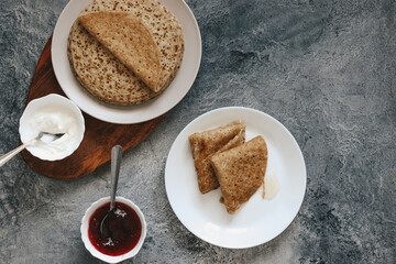 pancakes with honey and jam and fresh berries stand on a gray background, copyspace