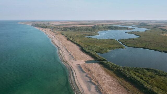 Aerial fly over beautiful empty endless wild beach with sand dunes and lake. A picturesque lagoon - lake Shabla in the north-eastern Bulgaria, which separated from the Black Sea by the sandbar..