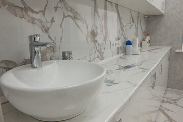 Sink and countertop in the cosmetology room, cabinets and marble tiles