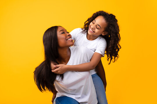 African American Girl Hugging Her Smiling Mom From Behind