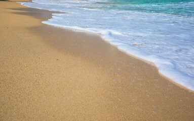 Rolling a wave with foam on a sandy shore