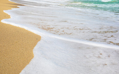 Rolling a wave with foam on a sandy shore