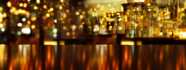 drinking glass in bar at night with orange lamp light with wood table party banner background.