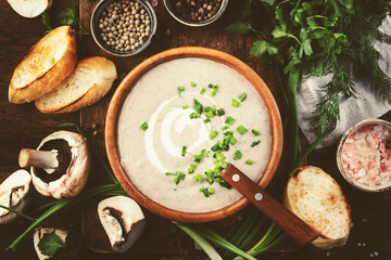 Creamy Mushroom Soup with croutons, spices and chives on rustic wooden table background