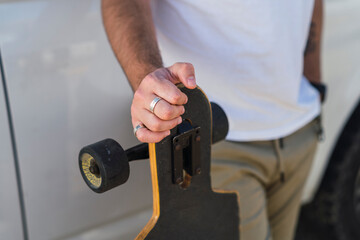 Skater holding a black skateboard; the focus is on the hand

