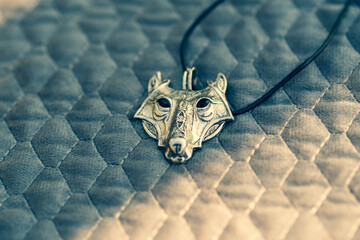 Pendant wolf head necklace silver color stainless steel shoot outside in a summer day closeup. Selective Focus. High quality photo
