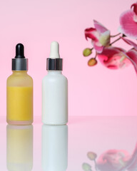 Three bottles of serum on a light pink background. Moisturizer, vitamin C, hyaluronic acid.
