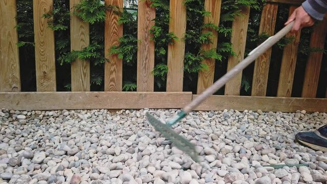 vista laterale di un rastrello che sistema la ghiaia nel giardino