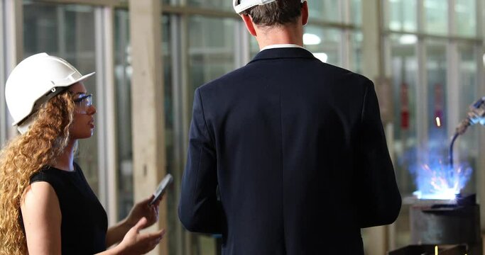 Manufacturing Factory female Mechanical Engineering programer Works on Personal Computer and man worker are working with Robotic Arm at industrial factory