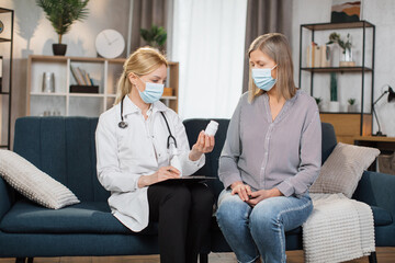 Fototapeta premium Seniors healthcare concept, treatment monitoring during pandemic. Caring confident woman doctor advicing her senior patient at home, talking about how to use prescribed medicines properly.