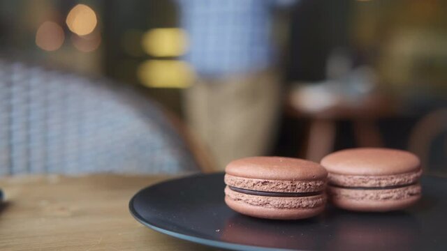 Close up of chocolate color macaroon on a plate in cafe 