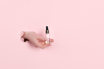 Female hands holding beauty bottles on abstract pink background. Horizontal view copyspace.