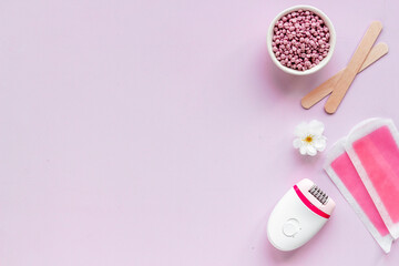 Cosmetics set for epilation with epilator and wax strips and flowers. Top view