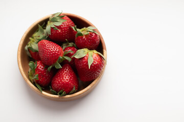 Juicy strawberry in a wooden bowl on a white background.