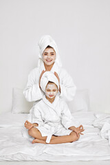 mother and daughter are sitting with towels on head and facial mask.