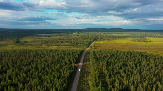Aerial drone view following a rv driving on forest road in sunny summer Sweden