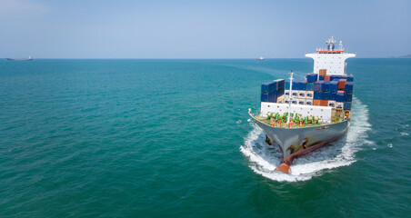 Aerial in front of cargo ship carrying container and running