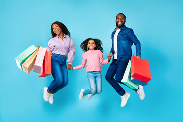 African American cheerful people jumping and holding shopping bags