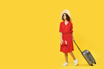 woman with suitcase going traveling on yellow background.