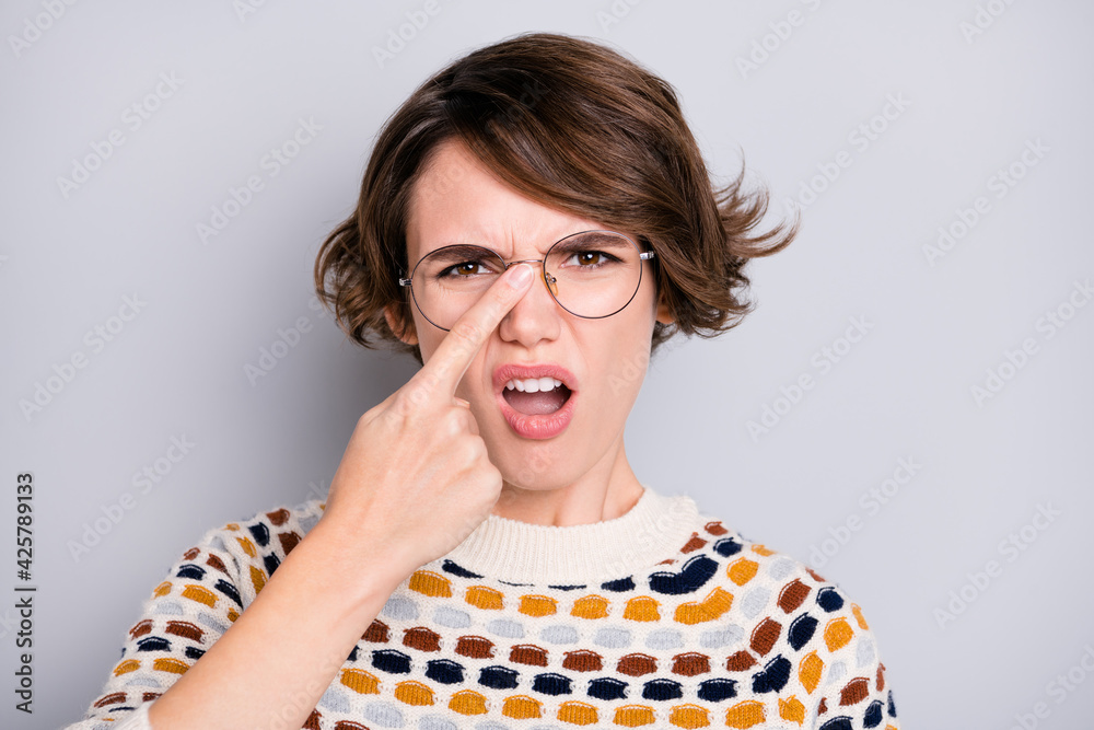 Poster portrait of attractive worried mad unhealthy girl touching specs bad vision isolated over grey paste