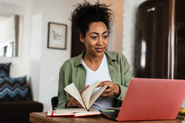 Black happy woman smiling while working with laptop at home
