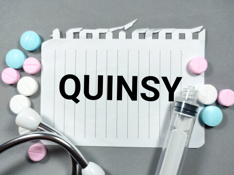 Selective focus.Word QUINSY with stethoscope and syringe on gray background.Medical concept.