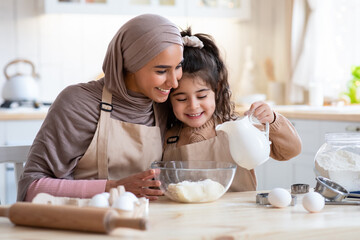 Obraz na płótnie Canvas Cute Little Arab Girl Baking Together With Her Islamic Mom In Kitchen