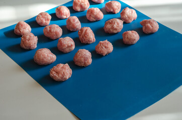 Raw shaped meatballs on blue.