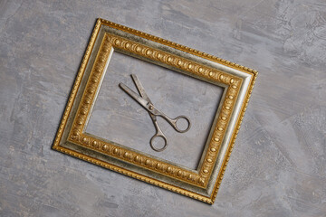 Old scissors in a bronze frame and a gray background. 