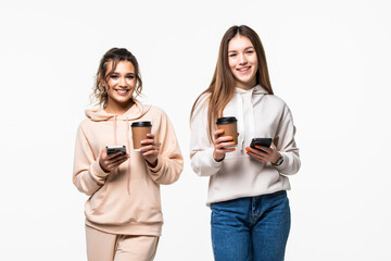 Two women drinking coffee to go use phone serf in social networks isolated on white background