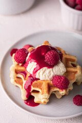 Freshly baked waffles with raspberry and ice cream on a plate