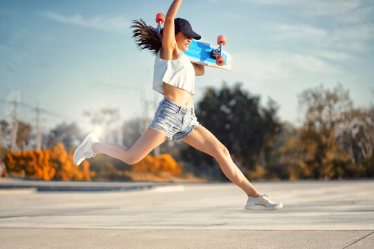 Asian Women Hold Surf Skate Or Skateboard Outdoors And Jumping On Beautiful Summer Day.