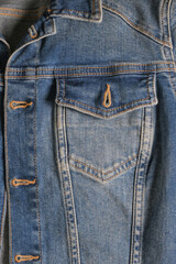 Denim pocket with a metal button on a blue jacket close-up with rough seams. High quality photo