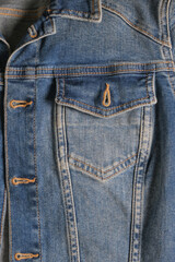 Fototapeta premium Denim pocket with a metal button on a blue jacket close-up with rough seams. High quality photo